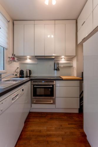 une cuisine avec des armoires blanches et des appareils en acier inoxydable dans l'établissement Appartement de luxe Champs Elysees Neuf, à Paris