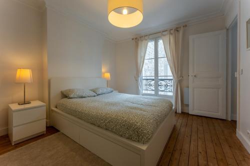 une chambre blanche avec un lit et une fenêtre dans l'établissement Appartement de luxe Champs Elysees Neuf, à Paris