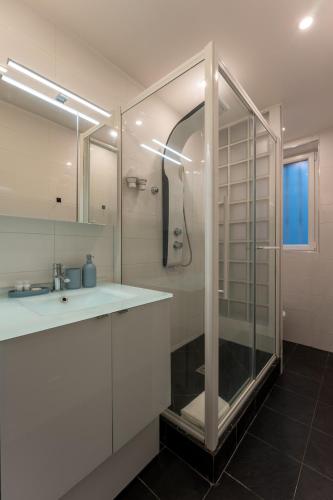 une salle de bain blanche avec une douche et un lavabo dans l'établissement Appartement de luxe Champs Elysees Neuf, à Paris