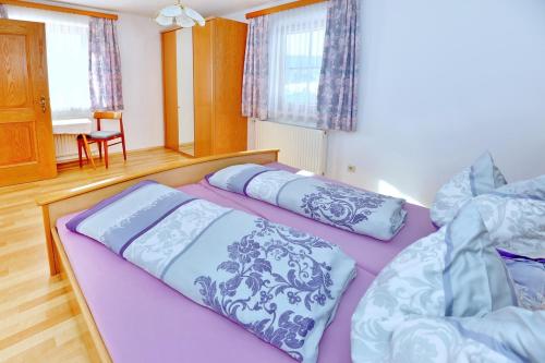 Haus Sonnenschein في فيلدكيرخن ان كرنتين: سريرين في غرفة نوم مع ملاءات أرجوانية وزرقاء
