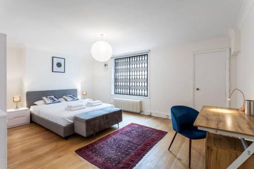ein weißes Schlafzimmer mit einem Bett und einem blauen Stuhl in der Unterkunft 2-bedroom split-level apartment in Notting Hill in London