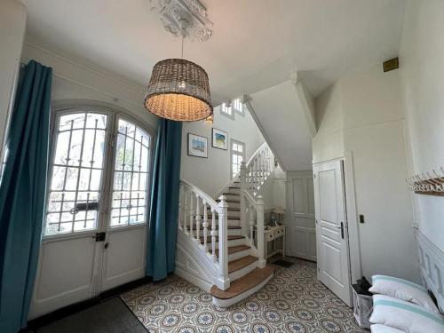 een kamer met een trap en een kroonluchter bij Villa La Clairière in Royan