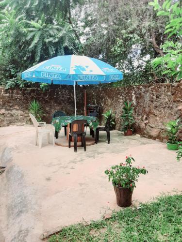 um pátio com um guarda-sol, uma mesa e cadeiras em KMK APARTMENTS em Kitwe