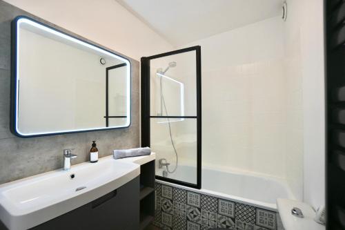 La salle de bains est pourvue d'un lavabo, d'une baignoire et d'un lavabo blanc. dans l'établissement Corto *2pas de la mer*parking*, à Concarneau