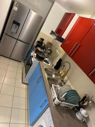 una cocina con fregadero y armarios rojos en Chambre d’hôte à 13 minutes de Disneyland, en Champs-Sur-Marne