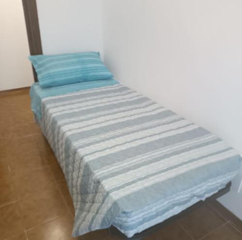 a bed with a blue and white striped blanket at Appartamento Dannunzio in Castelnuovo del Garda