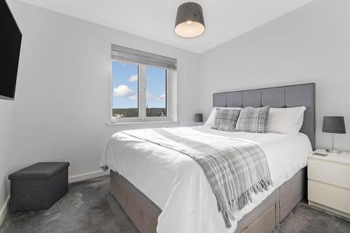 een witte slaapkamer met een groot bed en een raam bij Scenic getaway, open plan home! 2bed park for free in Eaglesham