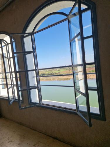 an open window with a view of the water at L'Oum Errebia in Azemmour