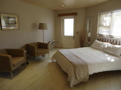 1 dormitorio con 1 cama, 2 sillas y ventana en Kasa Nama, en Edgemead