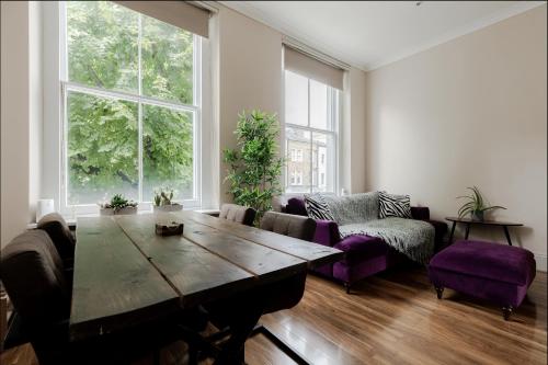 a living room with a wooden table and purple chairs at Spacious & stylish 1-bed flat in Primrose Hill in London