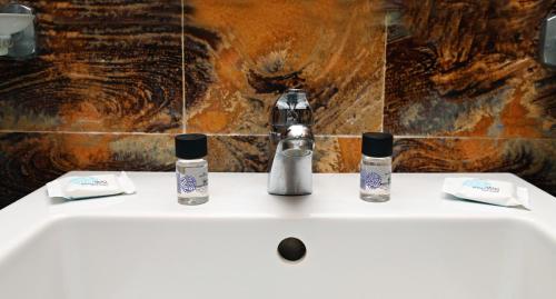 a bathroom sink with two bottles of soap on it at Aktis Hotel in Ancient Epidavros