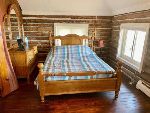 a bedroom with a wooden bed and a dresser at Restored historic log cabin & deck on Lake Erie in Luna Pier