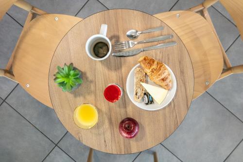 a round wooden table with a plate of breakfast food at B&B HOTEL Lyon Aéroport Saint-Quentin-Fallavier in Saint-Quentin-Fallavier