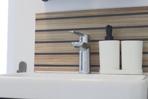 a bathroom sink with a faucet and two rolls of toilet paper at L'Escale cosy, proche Euroairport in Saint-Louis