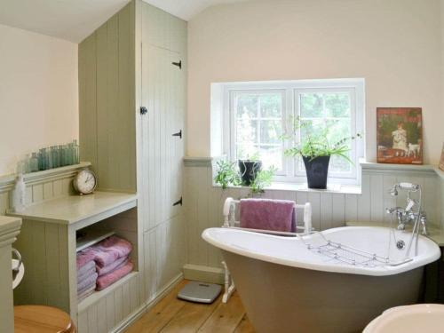 baño con bañera grande y ventana en Woodbine Cottage, en Studdon