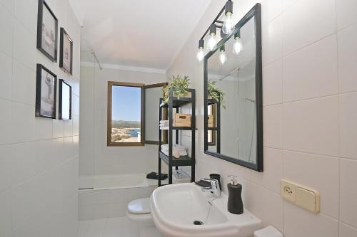 une salle de bain blanche avec un lavabo et un miroir dans l'établissement Perleta, à Capdepera