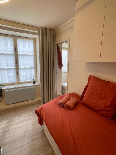 une chambre avec un lit avec des draps orange et une fenêtre dans l'établissement Comme une chambre d’hôtel au cœur de Lyon, à Lyon