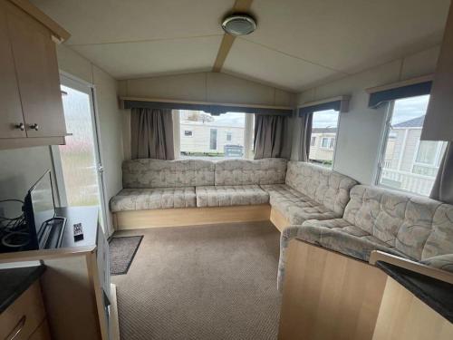 a living room with a large couch in a caravan at 2 Bedroom Caravan Stay, Central Beach, Leysdown in Leysdown-on-Sea