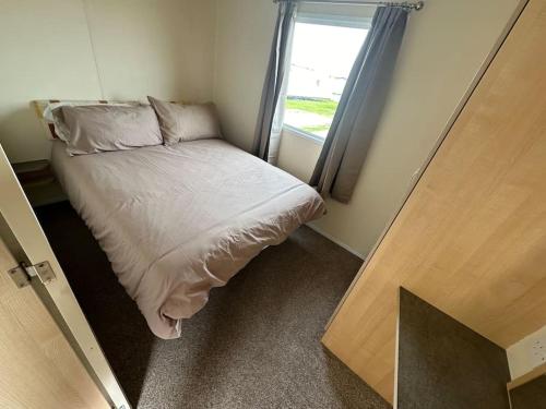 a small bedroom with a bed and a window at 2 Bedroom Caravan Stay, Central Beach, Leysdown in Leysdown-on-Sea