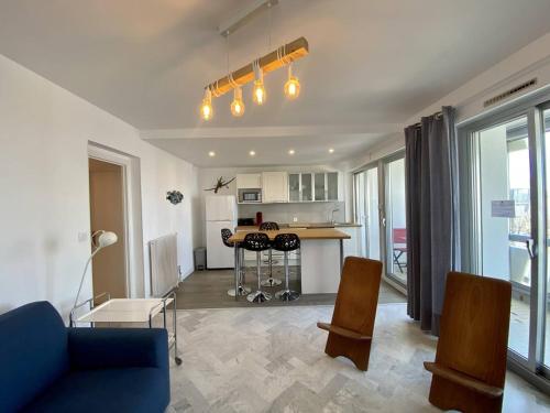 un salon avec un canapé bleu et une cuisine dans l'établissement BEL APPARTEMENT CLIMATISE CENTRE VILLE T2 - 4 PERSONNES AVEC LOGGIA VUE SUR MER, à La Grande Motte