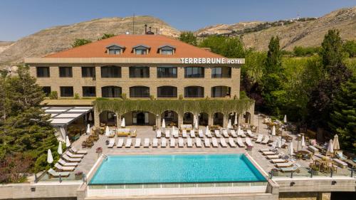 a hotel with a swimming pool and chairs and a building at Terre Brune Hotel in Kfardebian