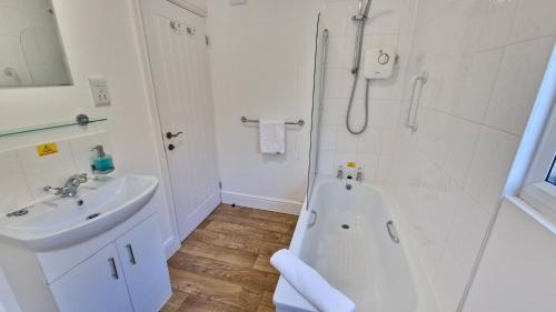 a white bathroom with a tub and a sink at 5 The Burrows in Braunton