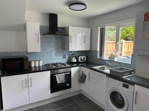 a kitchen with white cabinets and a stove top oven at Stunning 3-Bed House in Manchester in Manchester