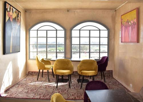 a room with chairs and a table and windows at L'Oum Errebia in Azemmour