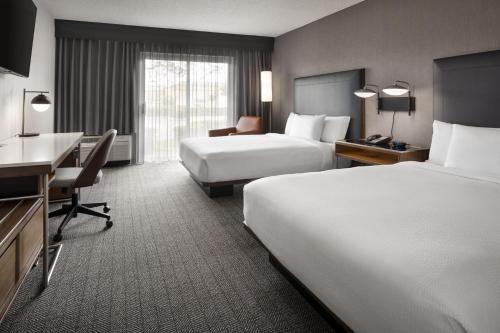 a hotel room with two beds and a desk at Courtyard by Marriott San Mateo Foster City in Foster City