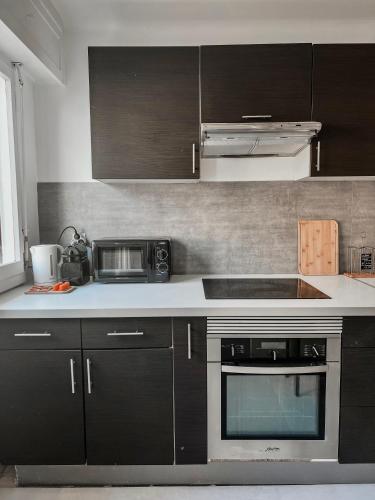 une cuisine avec des armoires noires et un four micro-ondes dans l'établissement Magnifique Appartement à 5 min des plages, à Antibes