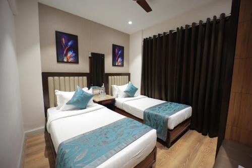 two beds in a hotel room with black curtains at The Byke Studio Pure Veg Apartment, Thane in Thane