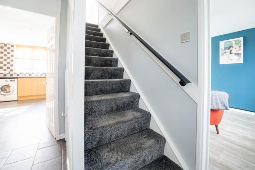 a staircase in a home with white walls and grey carpet at Gatwick Place - 4 bed 2 bath self contained house with private garden in Horley
