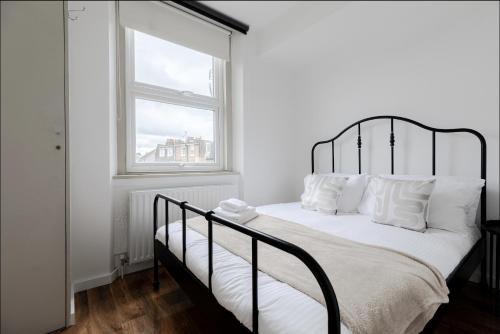 a bedroom with a black and white bed with a window at Primrose Hill Charming 1-Bed Flat in London