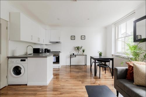 a kitchen and living room with a washing machine at Primrose Hill Charming 1-Bed Flat in London
