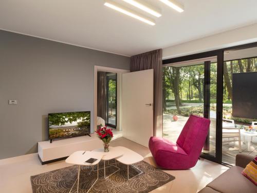 a living room with a pink chair and a tv at Rosevia Resort & Spa in Jastrzębia Góra