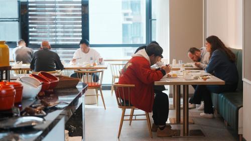 grupa ludzi siedzących przy stolikach w restauracji w obiekcie Zhangjiajie Hero Boutique Hotel w mieście Zhangjiajie