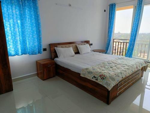 a bedroom with a large bed with blue curtains at Zanita Heights Seaview Apt in Bogmolo