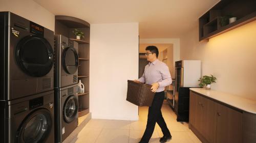 a man walking through a kitchen with two washing machines at Zhangjiajie Hero Boutique Hotel in Zhangjiajie