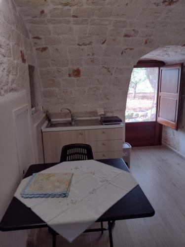 a kitchen with a table and a sink in a room at La casa di pietra in Monopoli