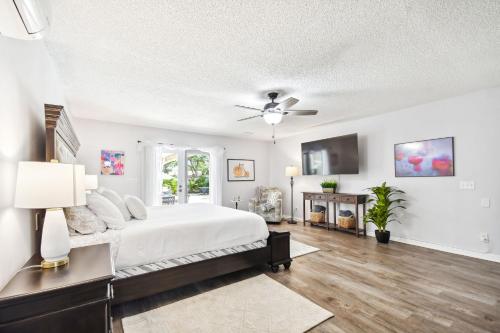 a white bedroom with a bed and a ceiling fan at The Palm by DNY Prime in St. Petersburg
