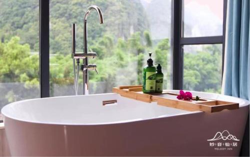 uma banheira na casa de banho com uma janela em Melody Inn em Yangshuo