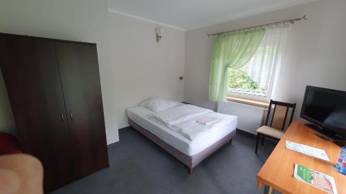 a small bedroom with a bed and a television at Leśny Dwór in Szczecinek