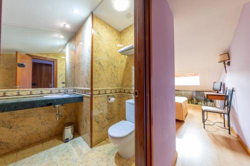 a bathroom with a toilet and a tub and a sink at H-A Puerta de la Villa in Almazán