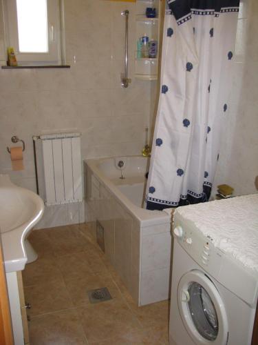 a bathroom with a tub and a washing machine at Apartment Megi in Tribunj