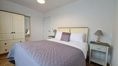 ein Schlafzimmer mit einem Bett, einer Kommode und einer Lampe in der Unterkunft 6 The Dunes in Braunton