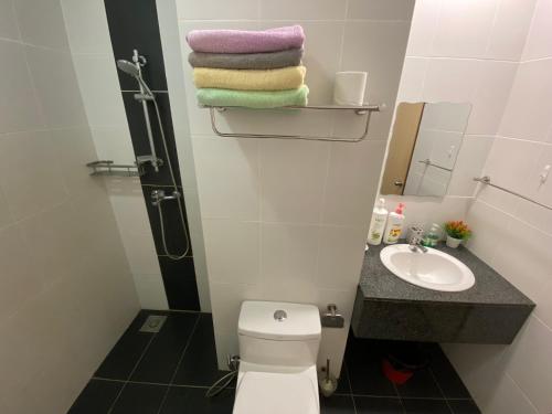 La salle de bains est pourvue de toilettes, d'un lavabo et de serviettes. dans l'établissement Kuching Imperial Suites Cozy Corner, à Kuching