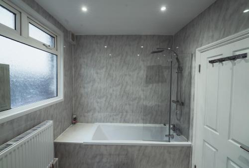 a bathroom with a bath tub and a window at One bedroom flat in Harrow. in Harrow