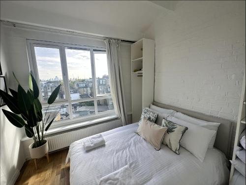Schlafzimmer mit einem weißen Bett und einem großen Fenster in der Unterkunft Primrose Hill Apartment with Balcony in London