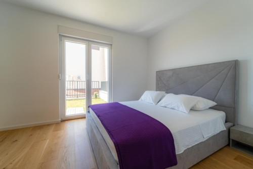 een slaapkamer met een groot bed en een groot raam bij Apartman Dvor in Podstrana