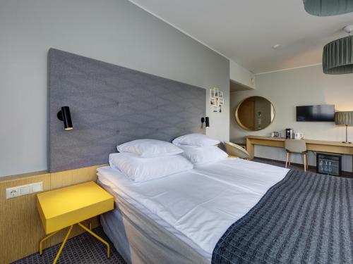 a bedroom with a large white bed with a yellow stool at Estonia Resort Hotel & Spa in Pärnu
